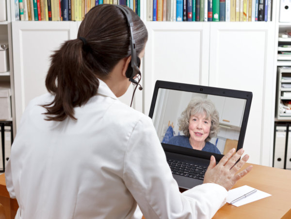 Nurse talking to elderly using laptop
