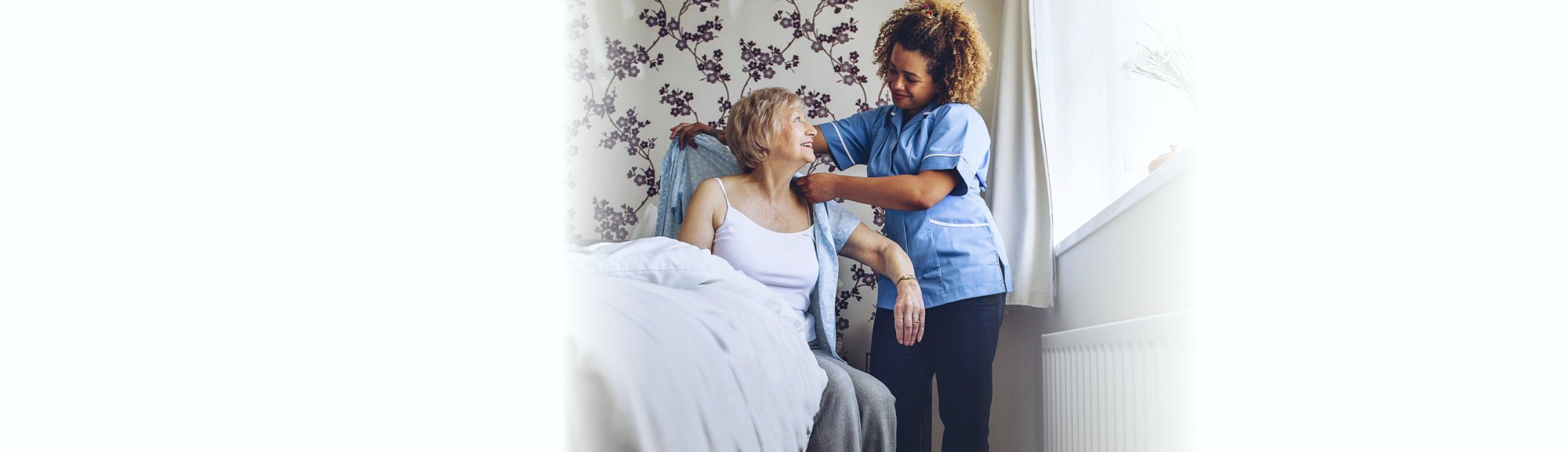 caregiver dressing her patient in bed