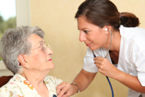 nurse checking the heart of an elderly woman